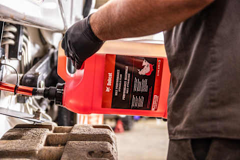 An Operator Adding Bobcat Warm Climate Max Performance Hydraulic Fluid in a Bobcat Machine