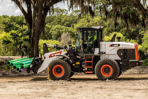 A Bobcat L285 Large Wheel Loader Transports Sewage and Drain Pipes Across a Jobsite Using a Pallet Fork