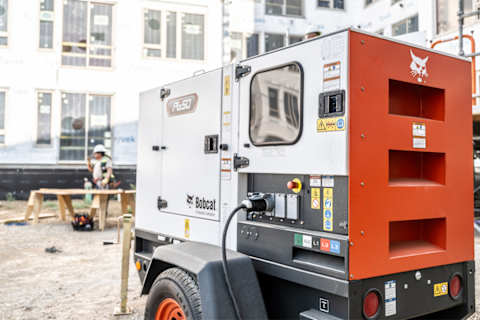 A Bobcat PG50 Portable Generator Positioned on Gravel at a Commercial Construction Site With Framing in the Background