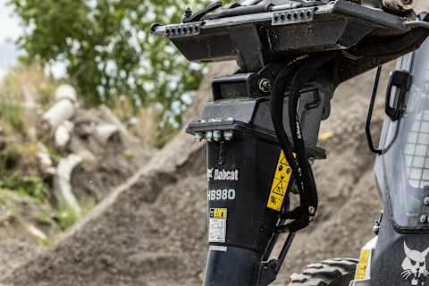 Close-up of a Bobcat HB980 hydraulic breaker attached to a Bobcat skid-steer loader working on a concrete slab