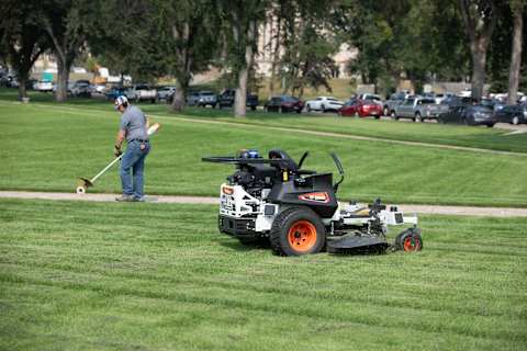 Operator details sidewalk while Bobcat ZT6200 autonomous zero-turn mower operates
