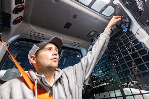 An operator using the storage compartment in the cab interior of a Bobcat T86-2 Pro Compact Track Loader