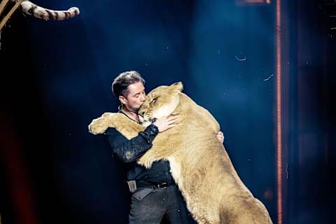 Martin Lacey-Krone tenant et étreignant un lion pendant un spectacle de cirque