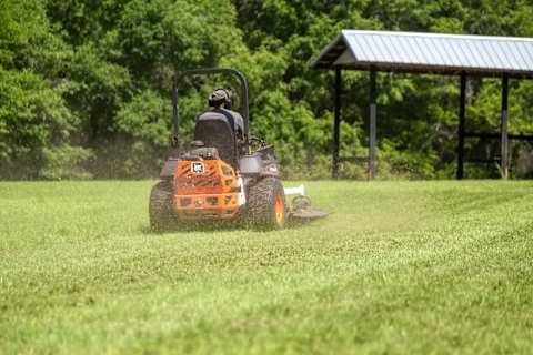 Rear view of an operator mowing grass at a commercial property using a Bobcat ZT7000 Zero-Turn Mower with a 61" AirFX Deck 