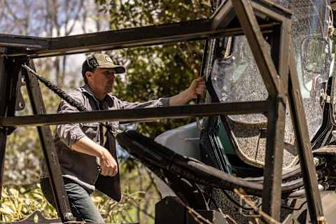 An operator entering a stationary Bobcat Pro T86-2 Compact Track Loader with a land management package at a tree farm