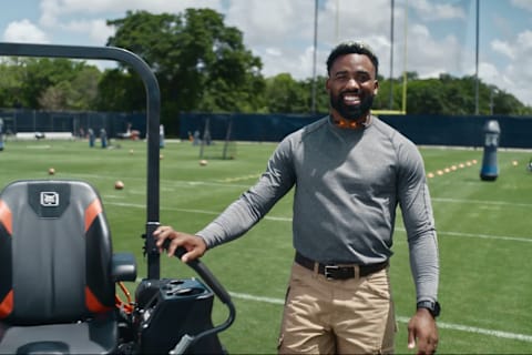 NFL Running Back Raheem Mostert stands next to a Bobcat ZT7000 zero-turn mower on a football field