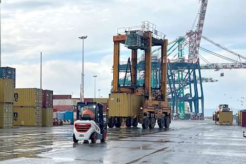 Bobcat diesel forklift travelling across the container terminal at the Port of Gioia Tauro, with port cranes behind