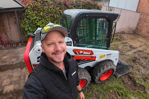 Josef Brunner, alias “Der Bagger Peppi”, die de S450 schranklader Bobcat bedient tijdens een terrasrenovatie in een moeilijk bereikbare achtertuin.