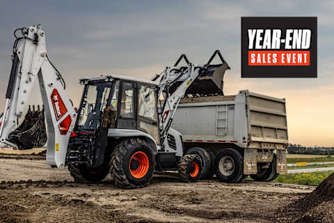 Bobcat B760 Backhoe Loader With Loader Bucket Attachment Loading Soil Into a Dump Truck at a Construction Site With a Year-End Sales Badge