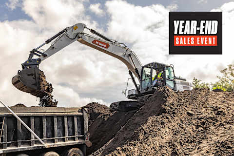 Bobcat E220 Large Excavator With Bucket Attachment Loading Soil Into a Dump Trailer at an Outdoor Worksite With a Year-End Sales Event Badge