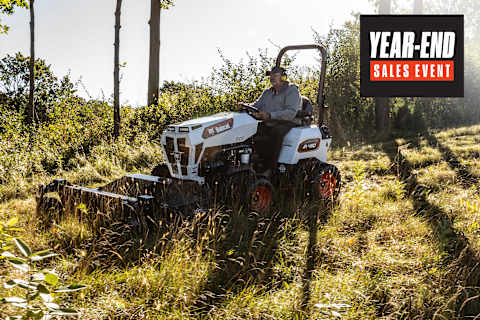 Bobcat AT450 articulating tractor with rough cut mower attachment mowing down tall overgrown grasses and brush on a hill
