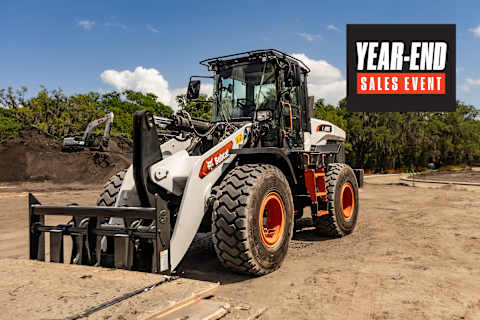 Bobcat L285 Large Wheel Loader With Grapple Attachment Parked on a Dirt Jobsite With an Excavator in the Background and Year-End Sales Event Graphic