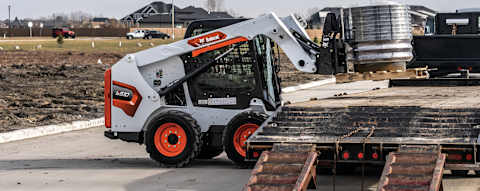 Right side view of an operator loading pallets on a truck using a pallet fork attached to a Bobcat S510 Skid-Steer Loader 
