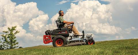 Operator Driving Bobcat ZT3000 Zero-Turn Mower Over Green Grassy Hill