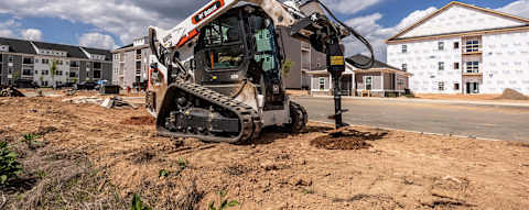 A Bobcat Pro T66-2 Compact Track Loader Uses an Auger Attachment to Drill Holes at a Residential Construction Site