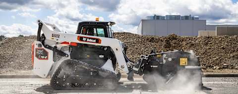 Bobcat T76-2 compact track loader using a wheel saw attachment to cut pavement along a roadside.