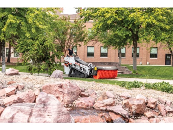 Groundskeeper sweeping a driveway with a Bobcat MT100 angle broom attachment