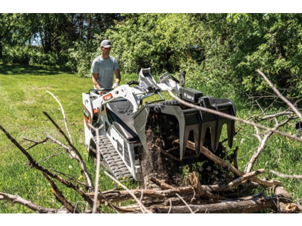 Landscaper moving large tree branches with a Bobcat MT100 grapple attachment