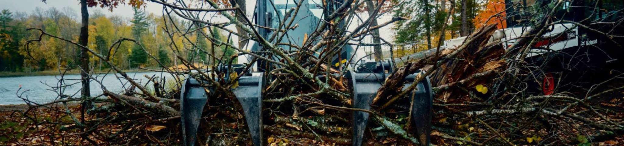 Bobcat Compact Track Loader With Grapple Attachment Moviing Logs.