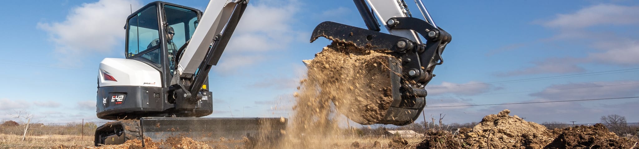 A Bobcat E42 Compact Excavator Scooping a Pile of Dirt