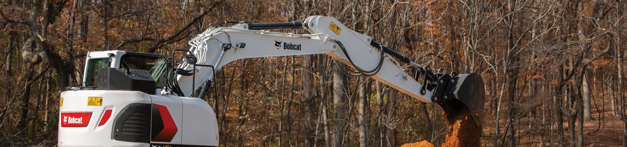 A Bobcat E145 Large Excavator Scooping a Pile of Dirt