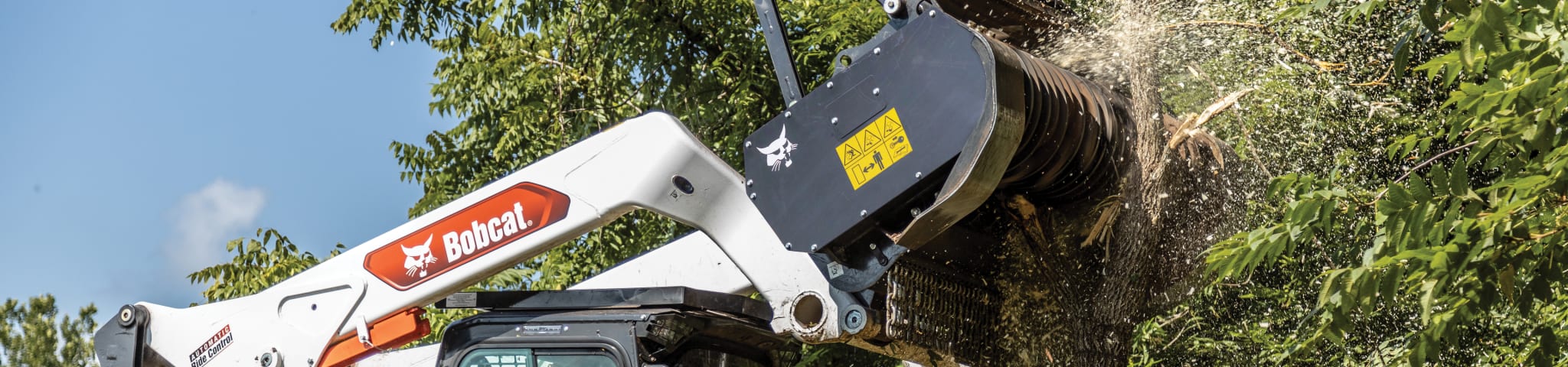 A Bobcat T86 Compact Track Loader Punches Into the Side of a Small Tree with the Drum Mulcher Attachment