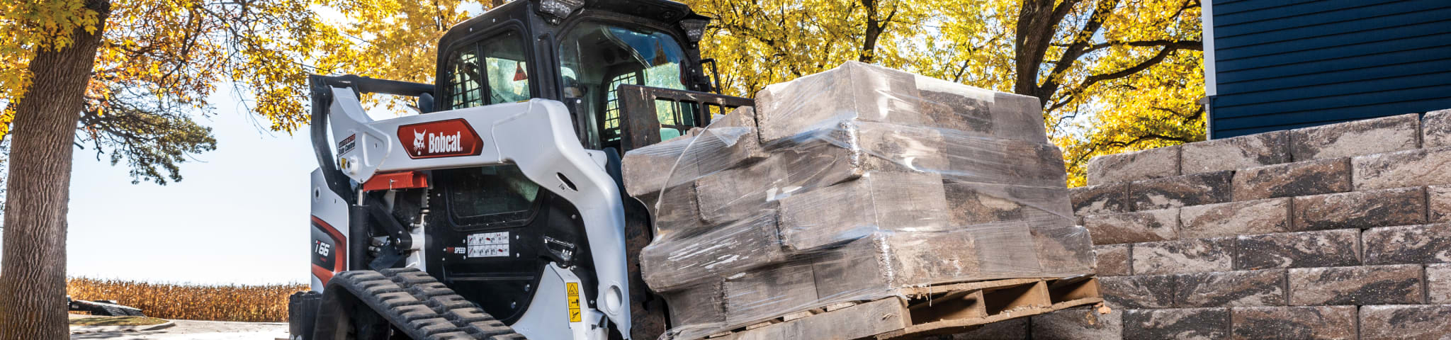 A Bobcat T66 Compact Track Loader Moving a Block with the Pallet Fork Attachment