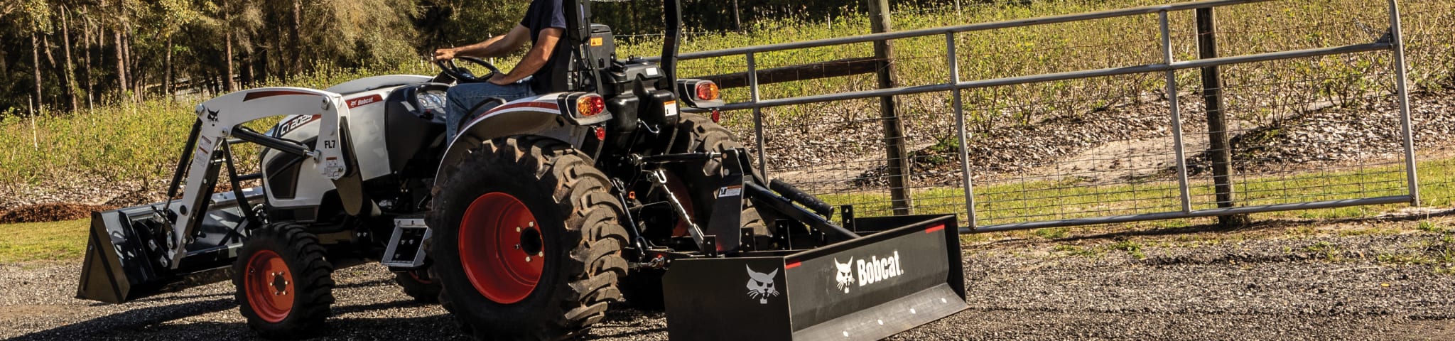 A Bobcat CT2025 Compact Tractor with a Box Blade Attachment on a Gravel Road