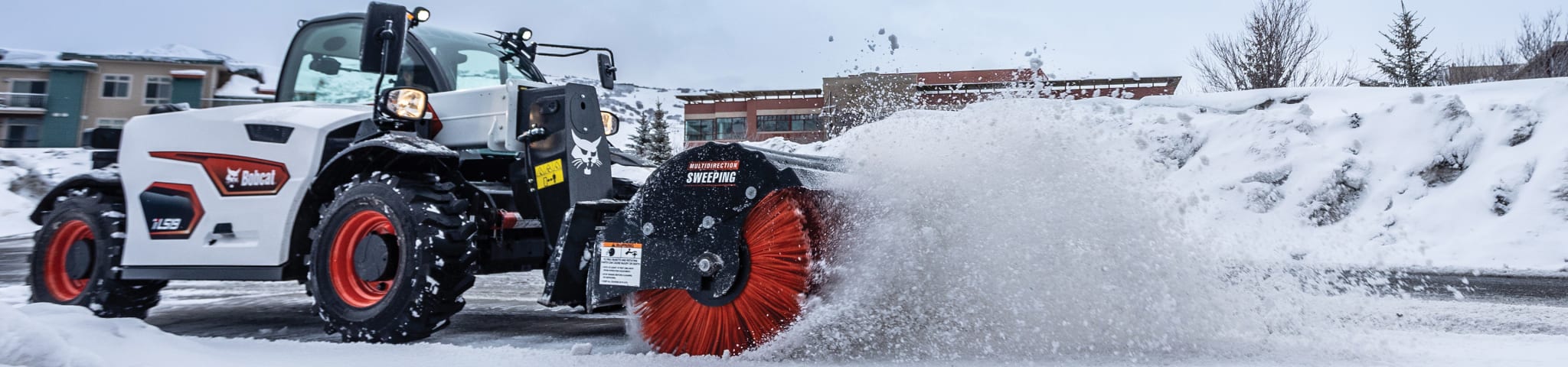 Operator uses a Bobcat TL519 Telehandler to brush snow off a path