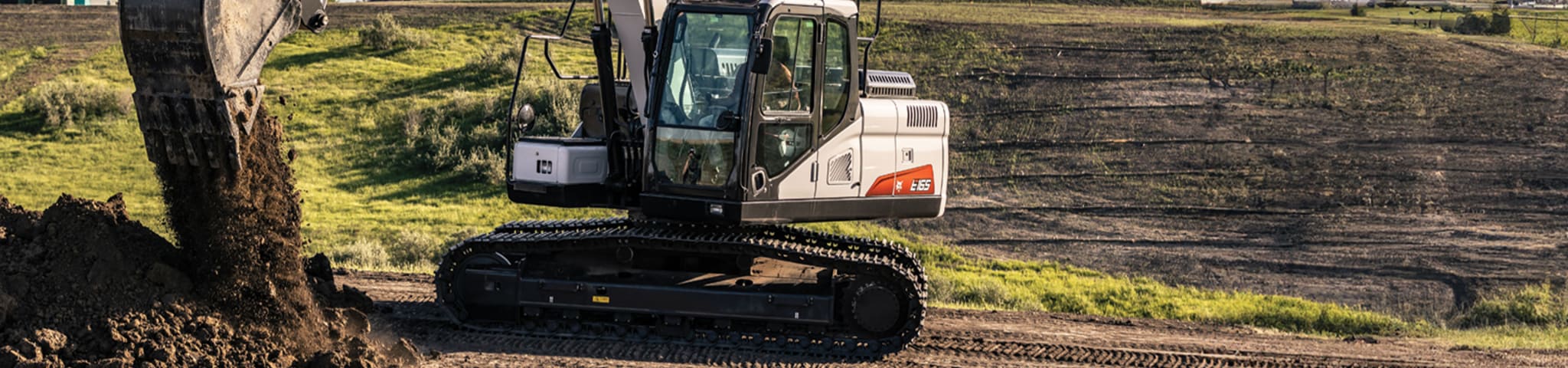 A Bobcat E165 Large Excavator Dumps Dirt on a Large Plot of Land 