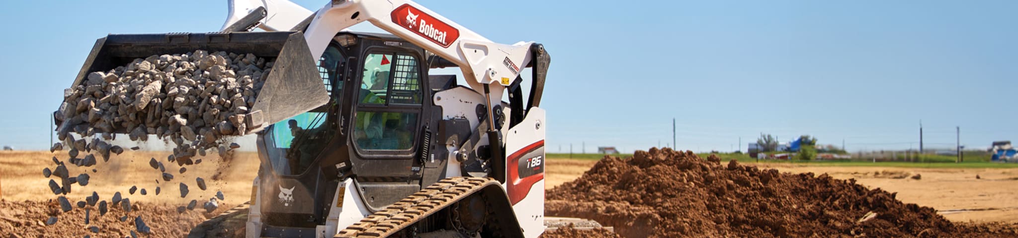 A Bobcat T86 Compact Track Loader Dumps a Bucketful of Rocks on a Construction Site 
