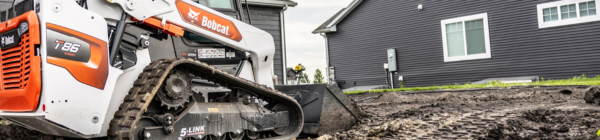  A Bobcat T86 Compact Track Loader Works in a Muddy Residential Yard