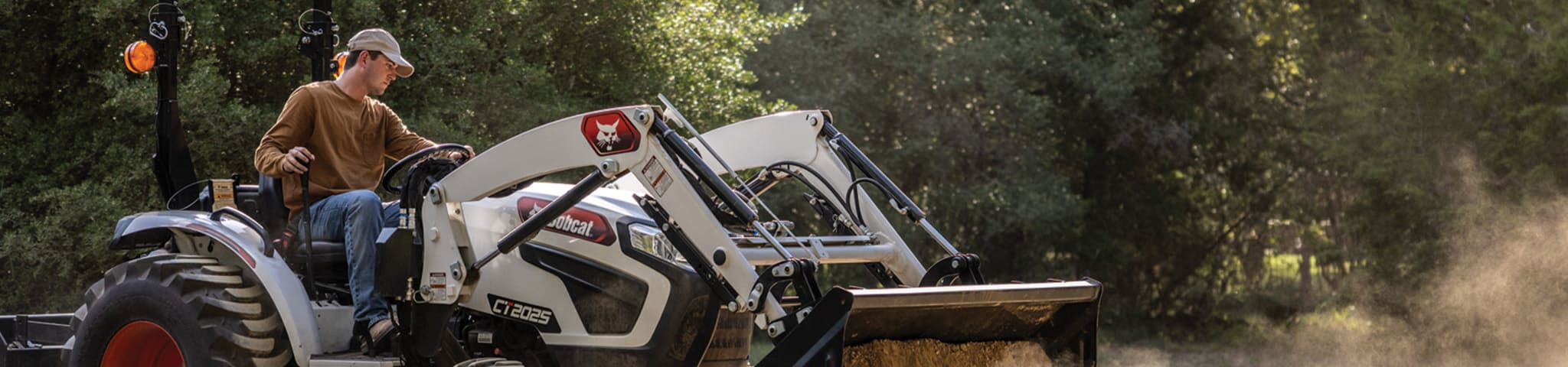 An Operator Uses a Bobcat CT2025 Compact Tractor With a Bucket Attachment to Dump Dirt 