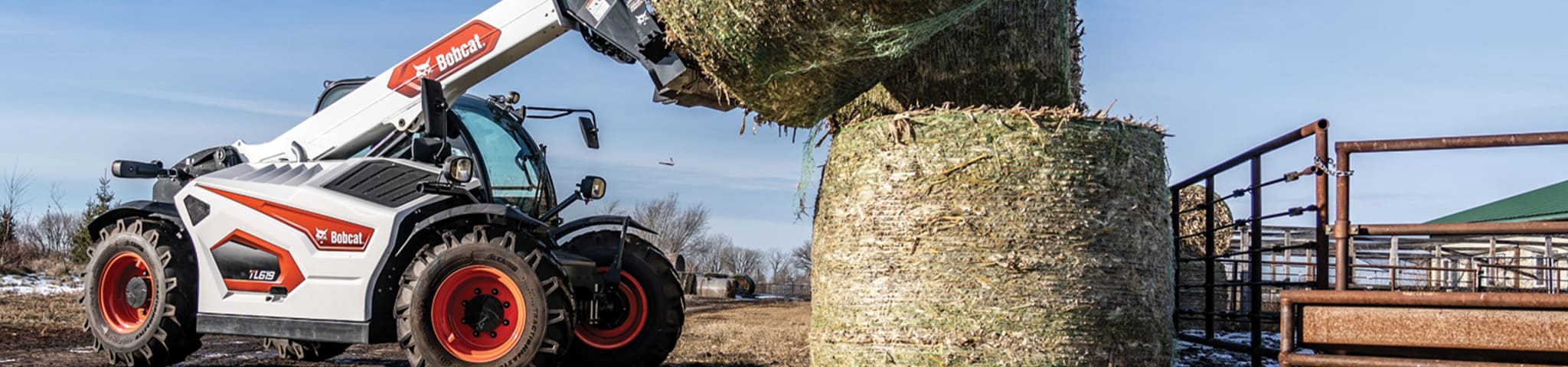 A Bobcat TL619 Telehandler Equipped With a Bale Fork Stacks Round Bales of Hay