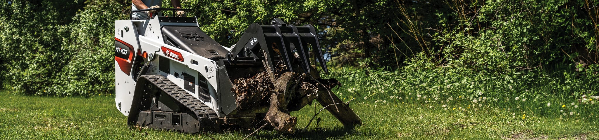 An Operator Uses a Bobcat MT100 Mini Track Loader With an Industrial Grapple to Pick Up Fallen Debris