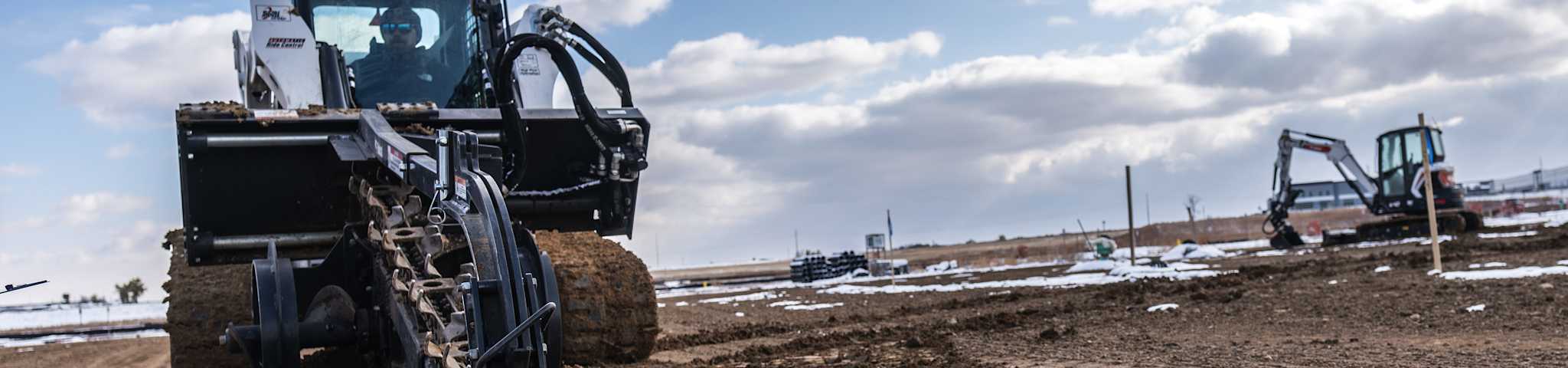 A Bobcat Compact Track Loader With Trencher Attachment Digs a Trench