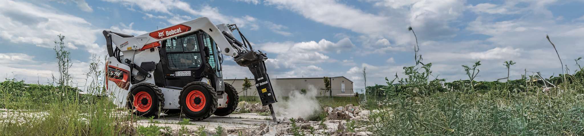 Right side view of an operator demolishing concrete at a commercial construction site using a nitrogen breaker attached to a Bobcat S76 Skid-Steer Loader