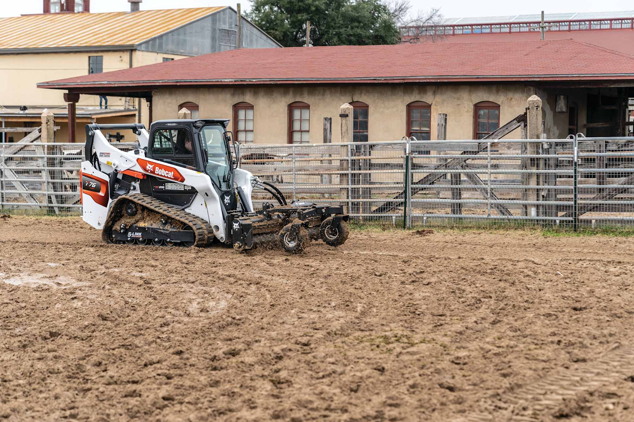 Bobcat T76 compact track loader operating a soil conditioner attachment on a muddy jobsite.