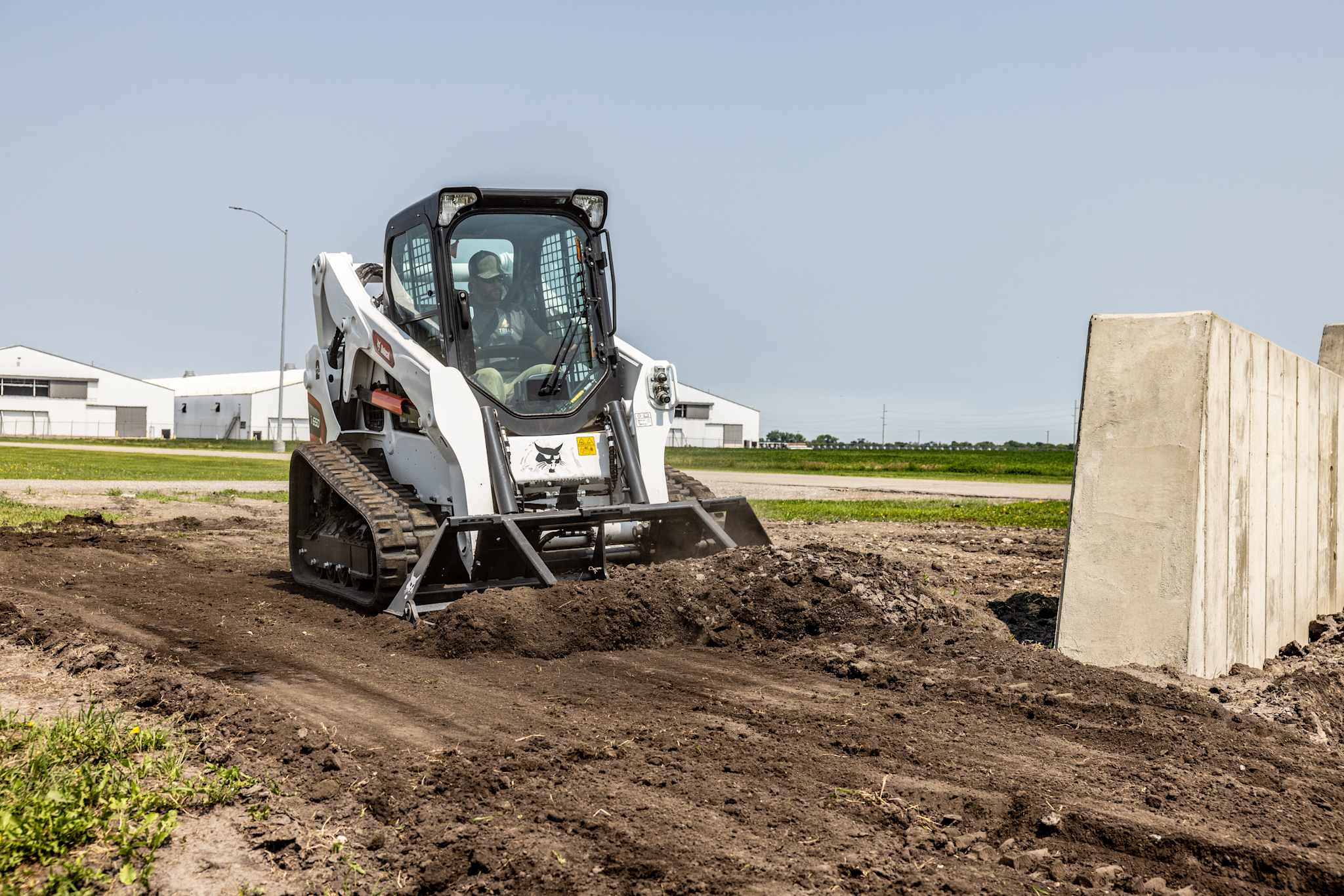 Bobcat compact track loader leveling dirt with precision on an open jobsite.