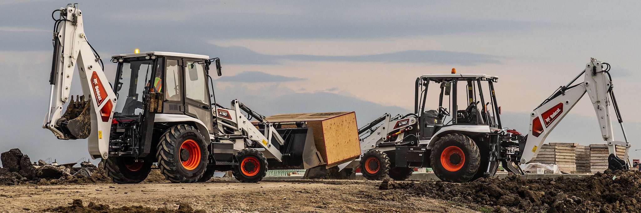 Two Bobcat b760 Backhoe Loaders, Left Machine Carrying Box, Right Machine Digging Dirt with Backhoe
