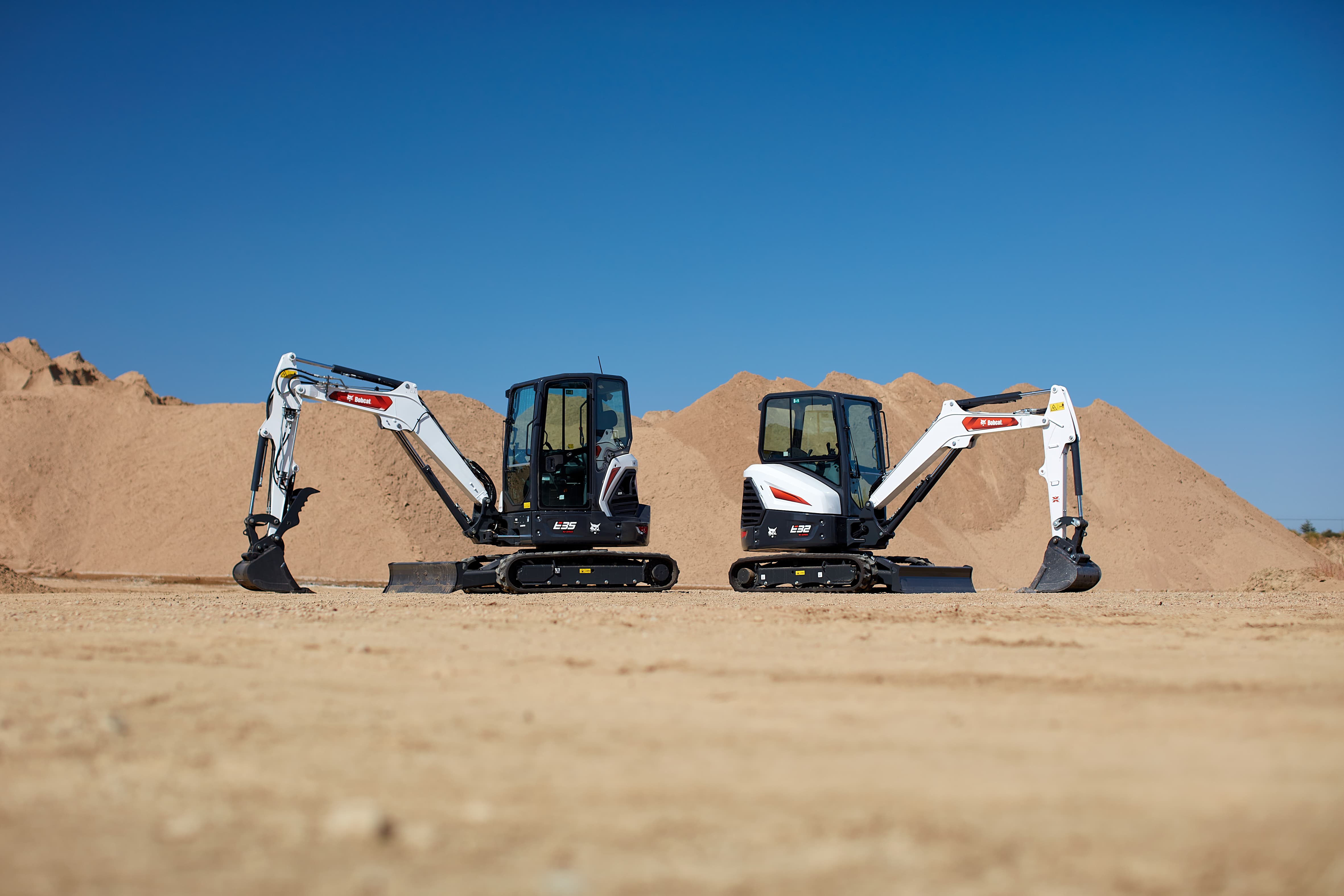 Two Bobcat 3–4 ton compact excavators positioned on a dirt jobsite