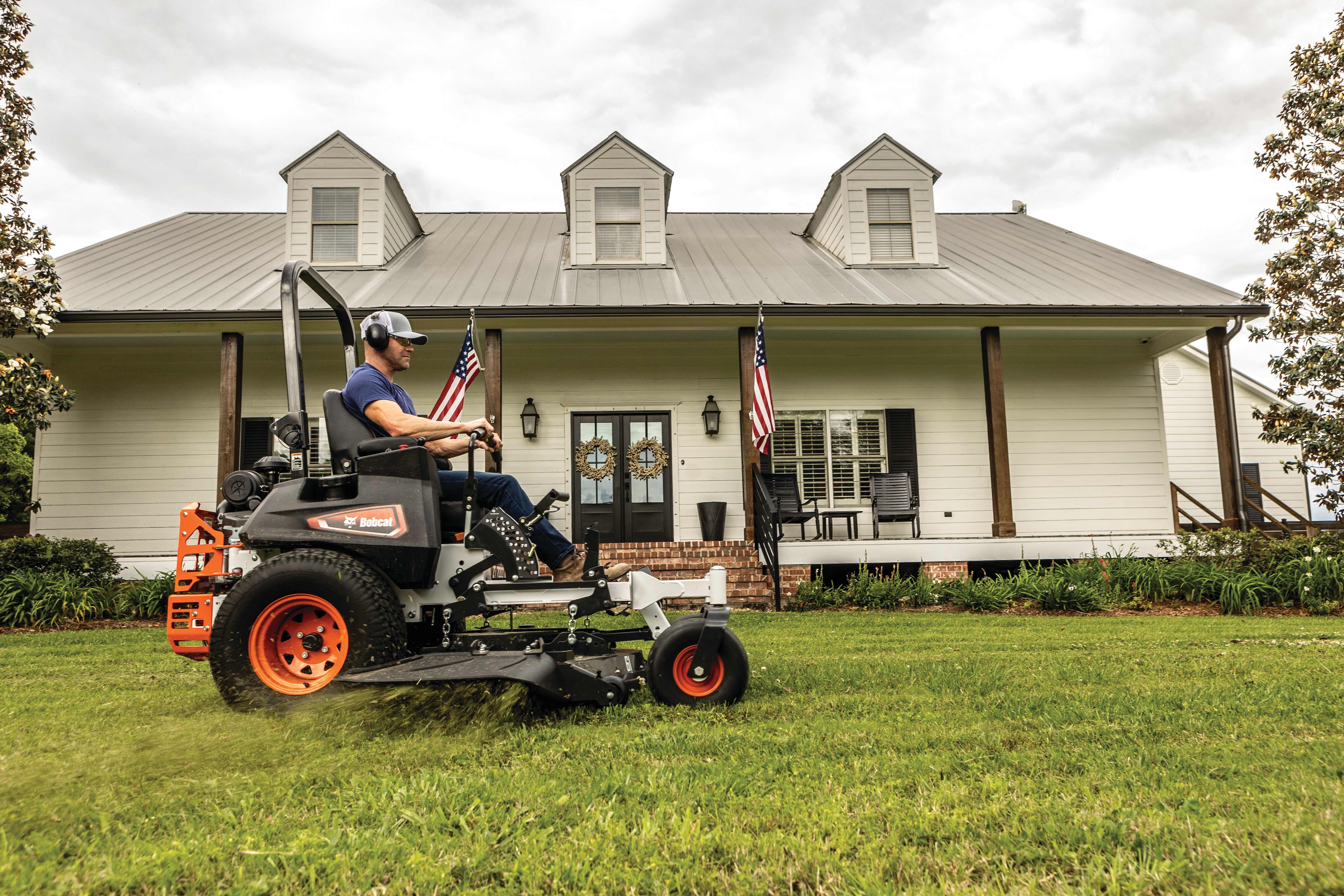 Bobcat ZT7000 Zero-Turn Mower with operator on lawn in front of house