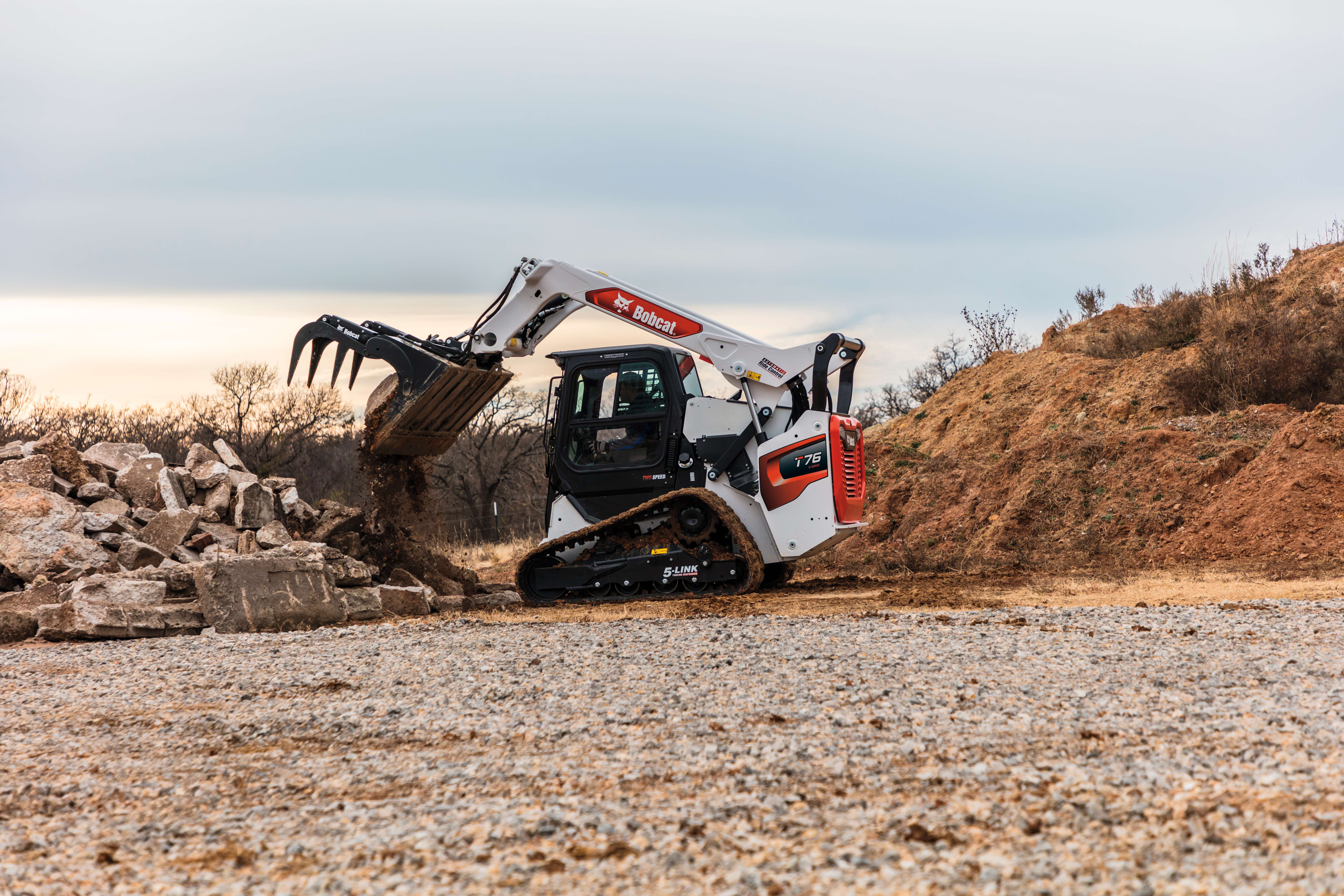 An Operator Uses a Bobcat Compact Track Loader and an Industrial Grapple to Move Large Chunks of Cement 