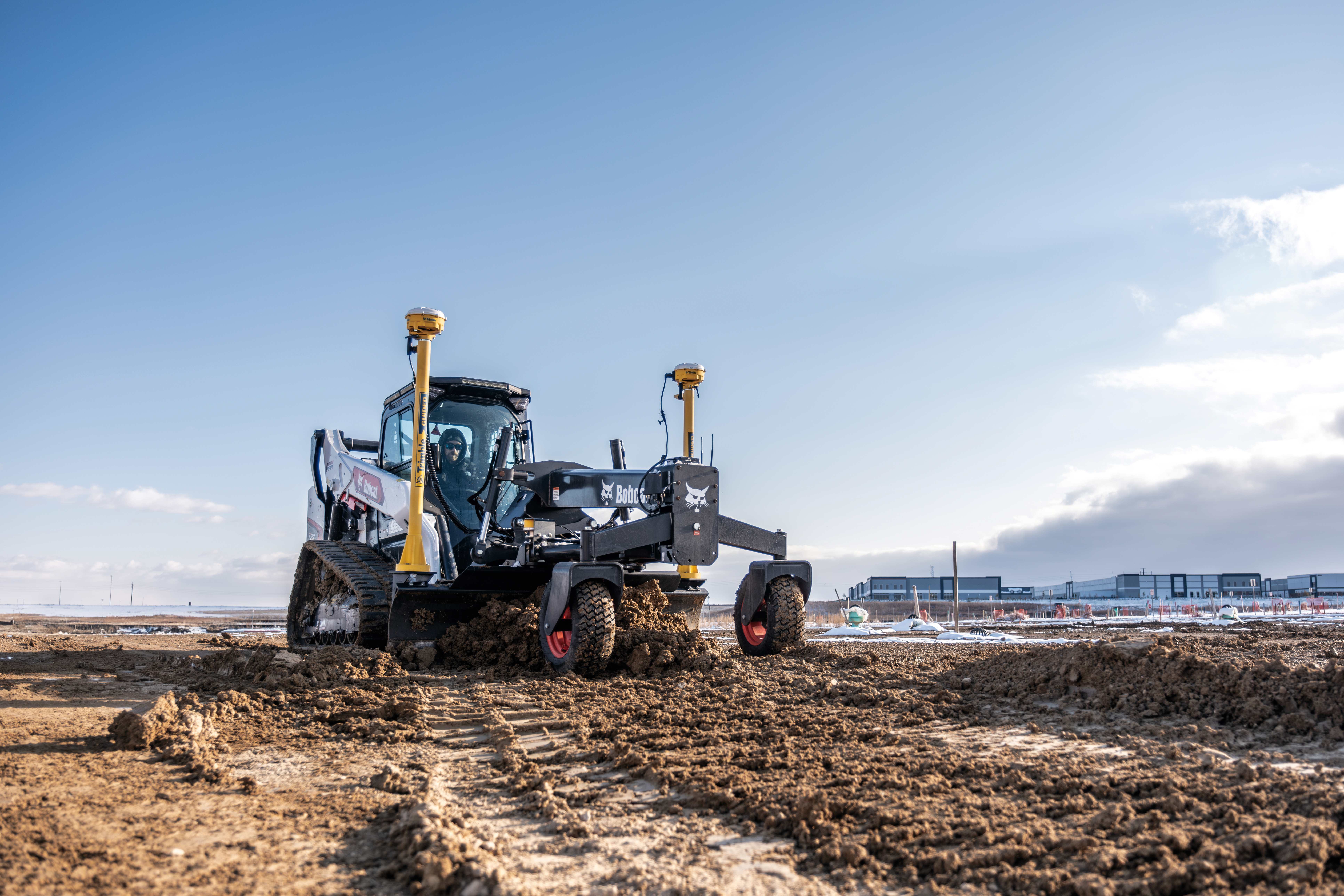 An Operator Uses a Bobcat T86 Compact Track Loader Equipped With a Grader Attachment to Level the Ground 