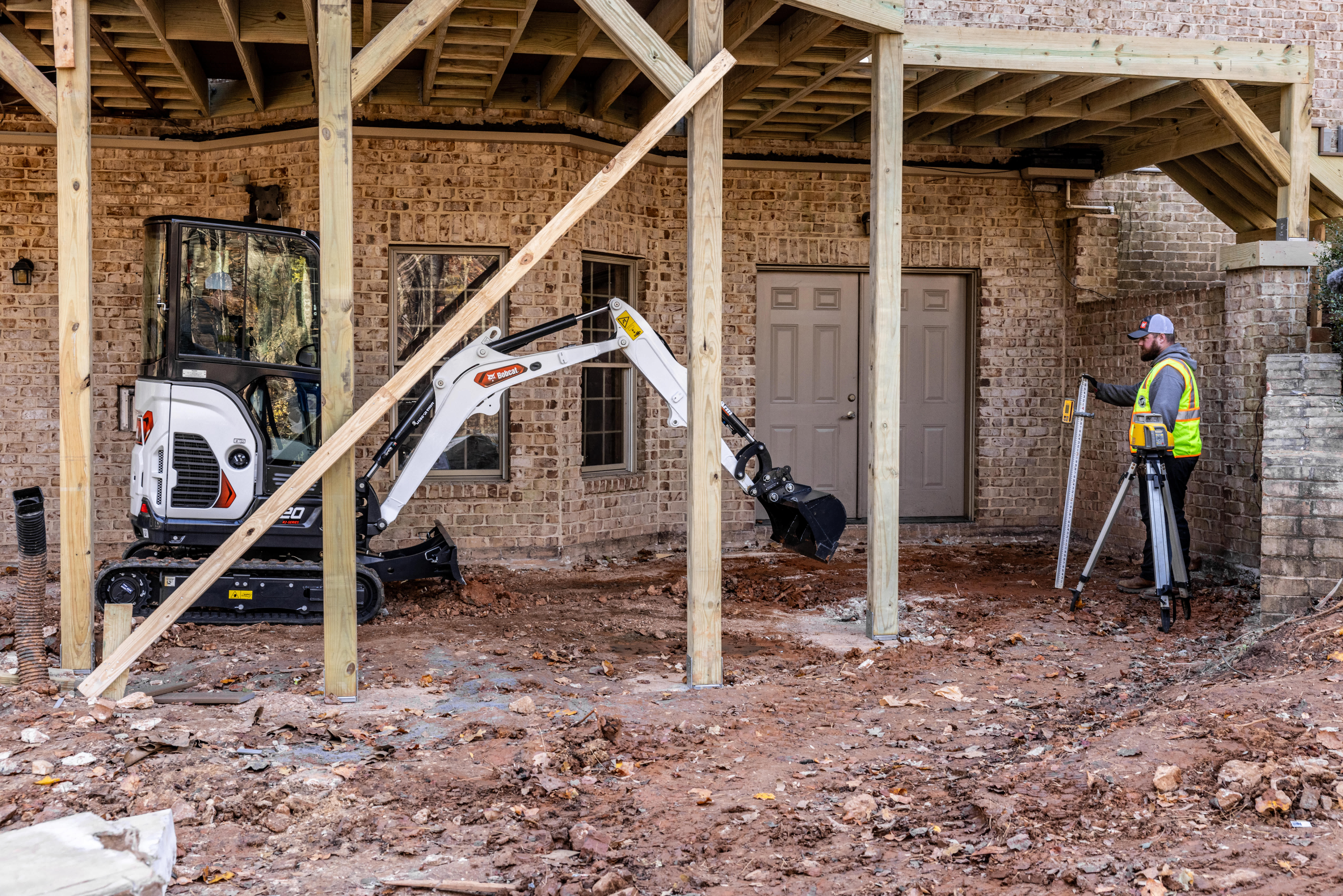 Bobcat compact excavator working beneath a residential deck during construction