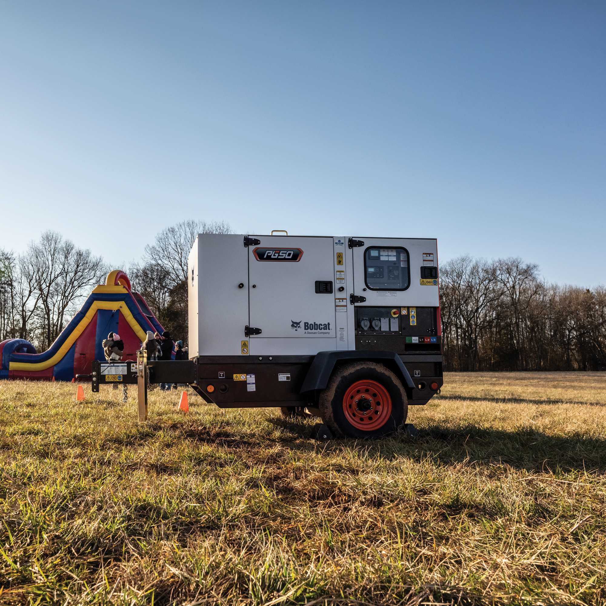 A Bobcat PG50 Portable Generator powering a bounce house in a field