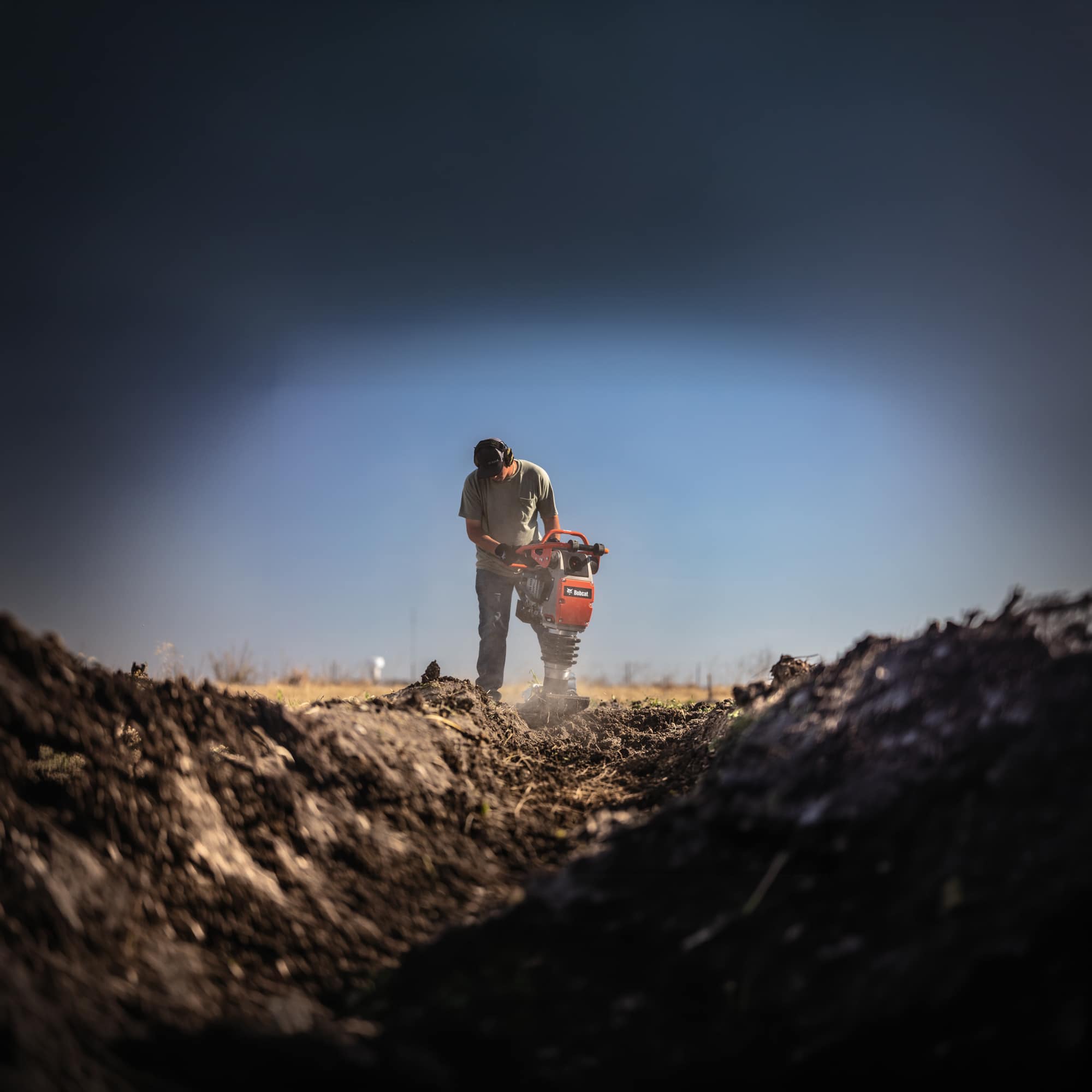 An operator packing dirt using a Bobcat R68P Upright Rammer