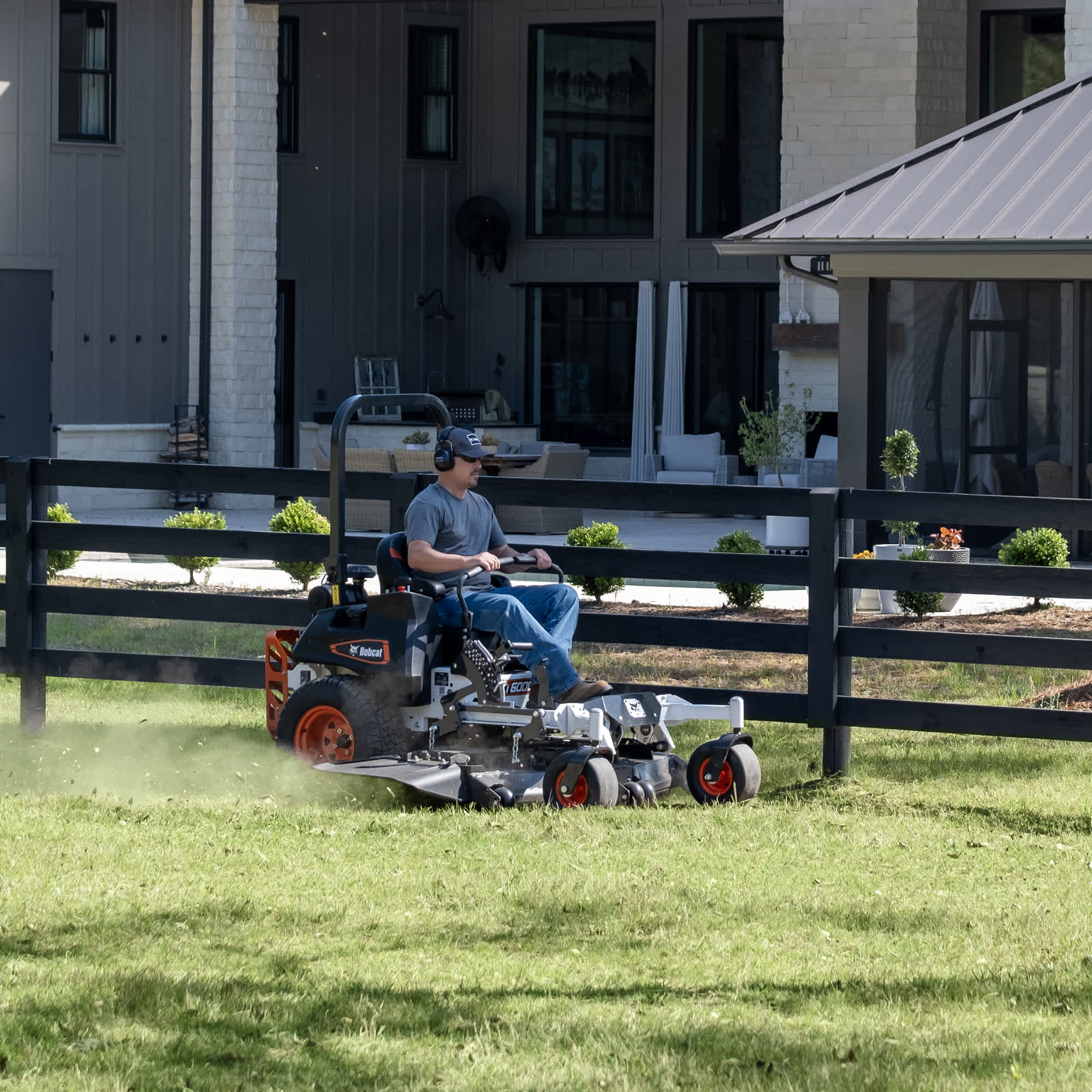 Front right quarter view of an operator mowing grass at a commercial property using a Bobcat ZT6000 Zero-Turn Mower with a 61" AirFX Deck