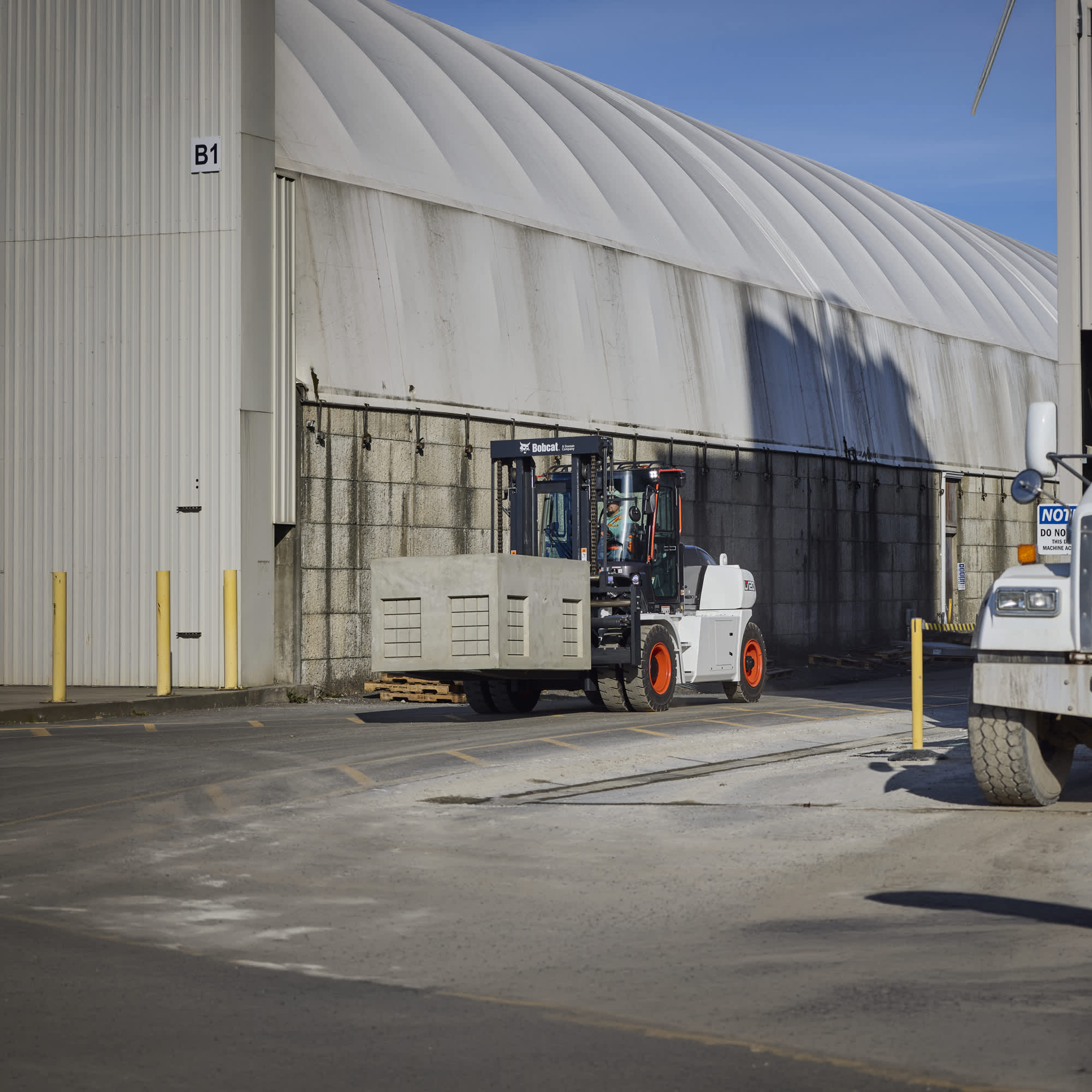 A Bobcat D120S-9 Internal Combustion Pneumatic Tire Forklift hauling pre-cast concrete at a job site