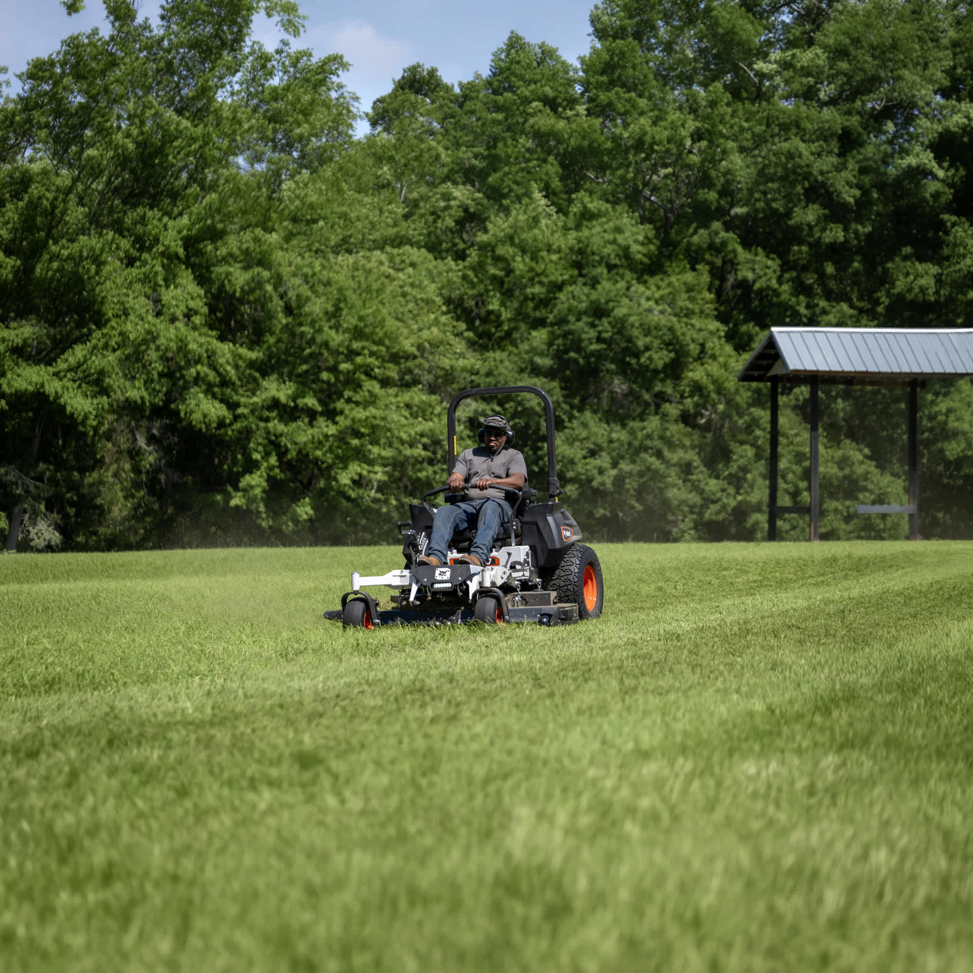 Front view of an operator mowing grass at a commercial property using a Bobcat ZT7000 Zero-Turn Mower with a 61" AirFX Deck